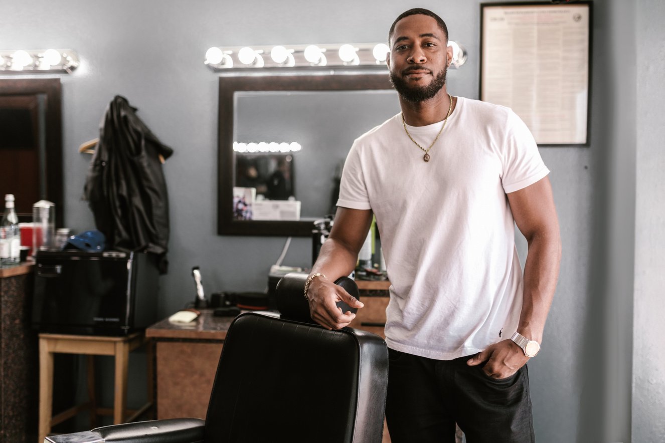 A Barber in a White Shirt Leaning on a Barber Chair