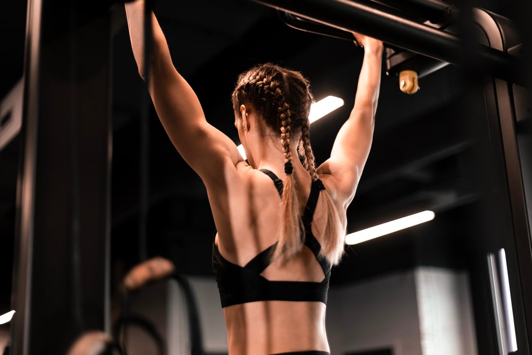 Women doing pull ups training arms in the gym. Upper body training.