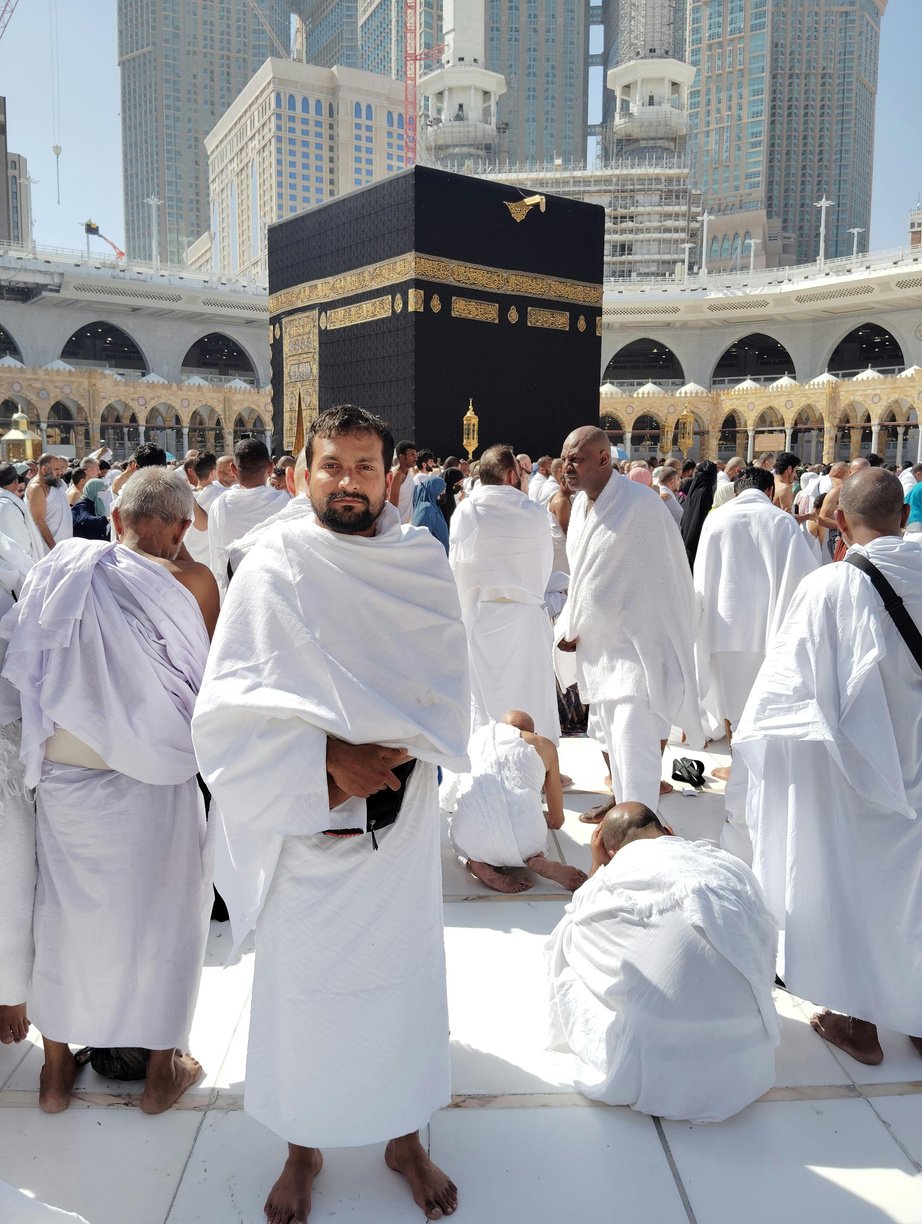 A man in white robes standing in front of the kaaba